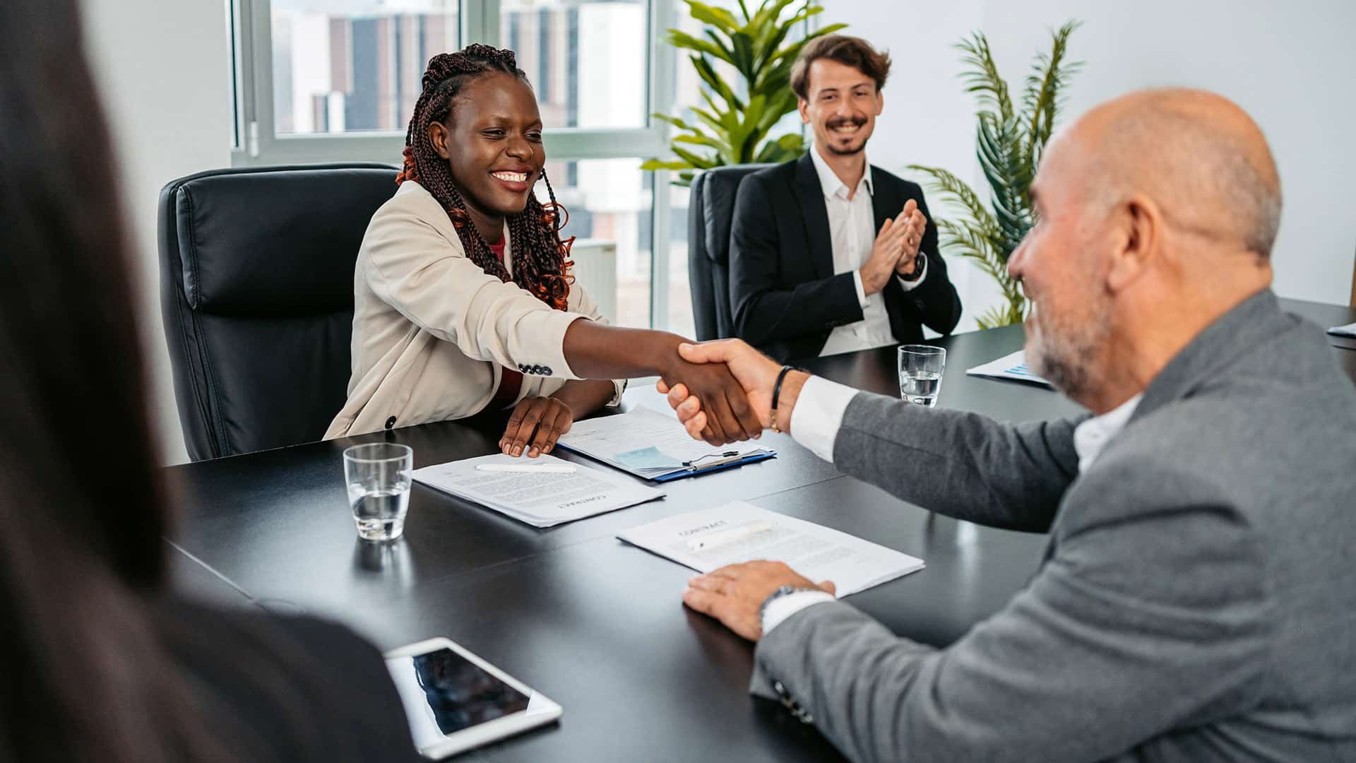 Multi-racial employees shaking hands over a table