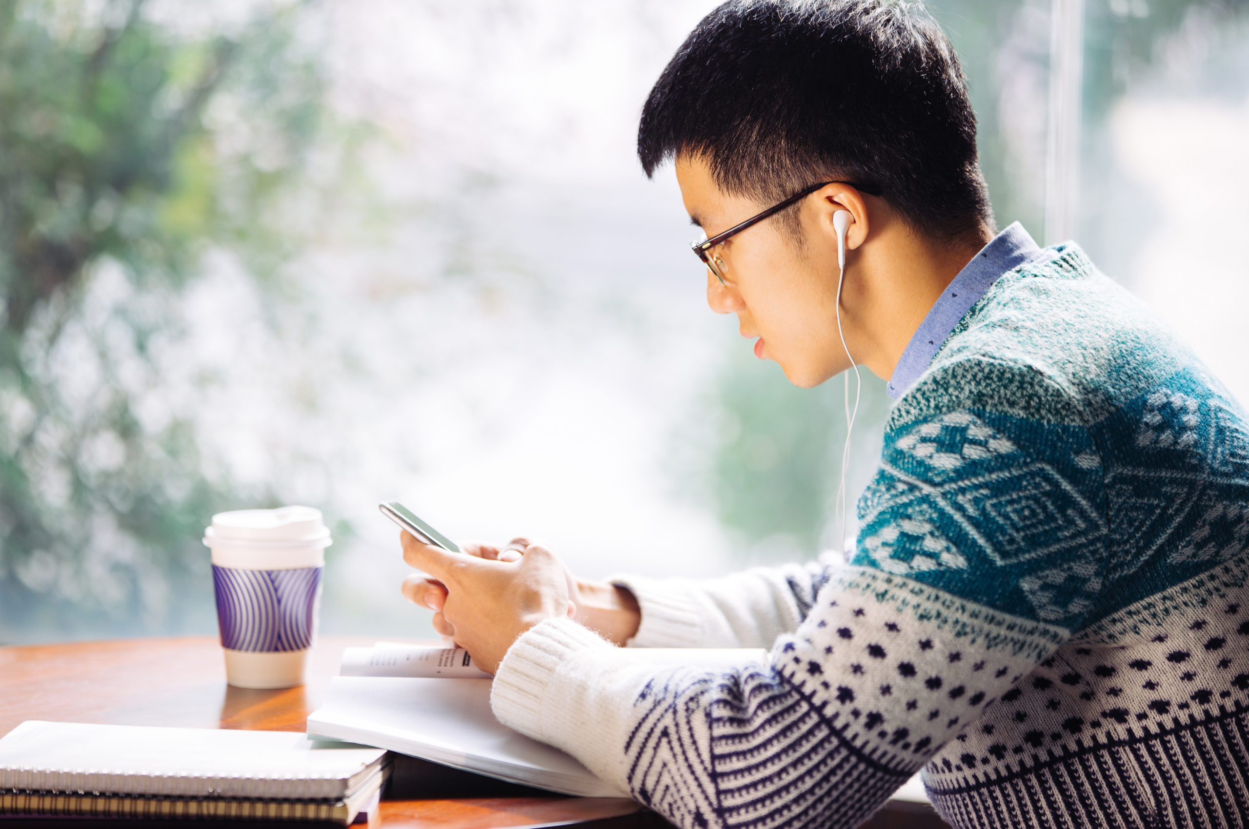 young asian man student holds mobile phone