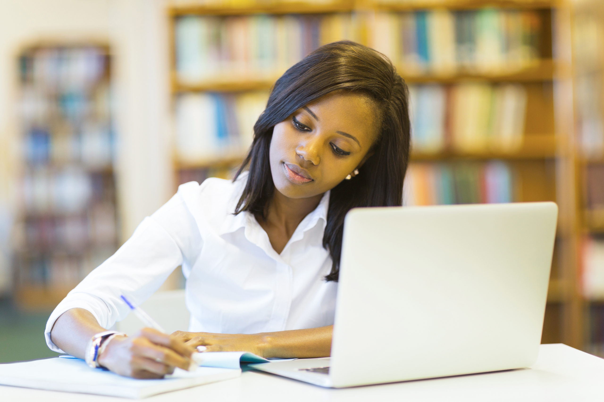 Young woman takes notes in front of a computer