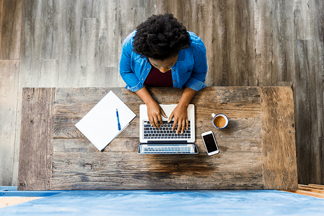 Aerial shot of a person sitting at a desk on their laptop.